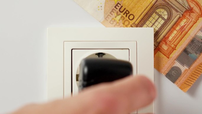 通过适配器将家用设备电源连接到电源插座，并插入一张欧元钞票。家庭财务和节约家庭预算的概念