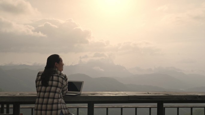 自由职业女性在假期用笔记本电脑看风景