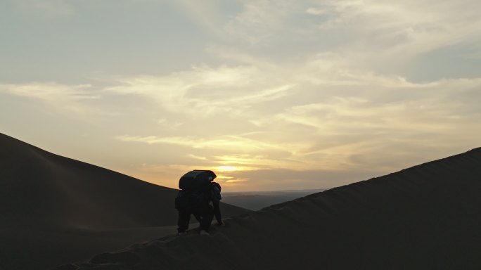 库木塔格沙漠上夕阳晚霞中抛沙的人爬沙山