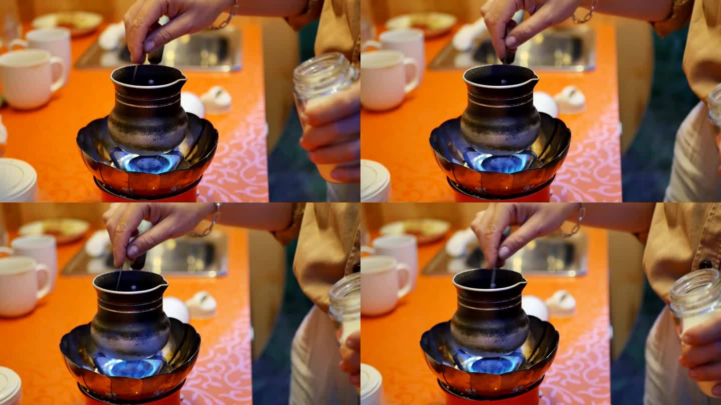 在拖车露营车的厨房里，用便携式燃气燃烧器制作天然cezve咖啡的特写镜头。女性用勺子冲咖啡时，用手倒