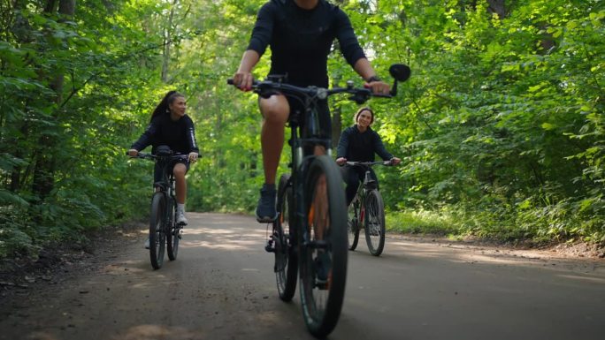 夏日里在森林里骑自行车的运动妇女，地面上的自行车车轮的细节视图