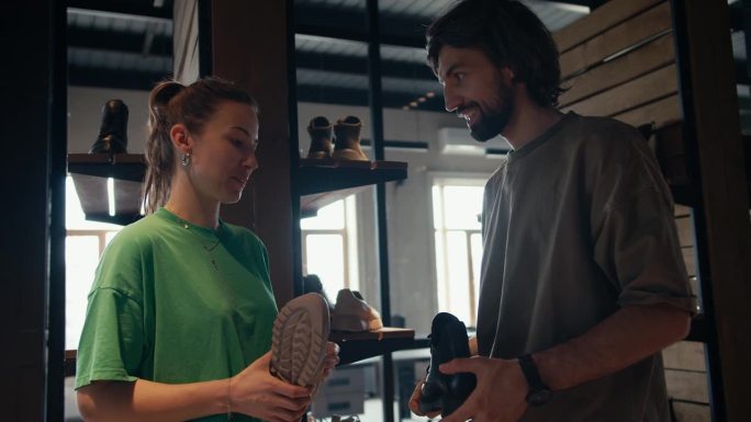 一个顾客、一个穿棕色t恤的男人和一个穿绿色t恤的鞋店女职员正在谈论选鞋