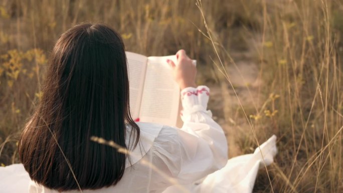 日落时分，一个女人在草地上看书的特写