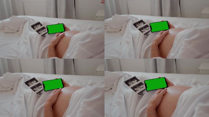 孕妇手持绿色色度键屏的手机触摸腹部。