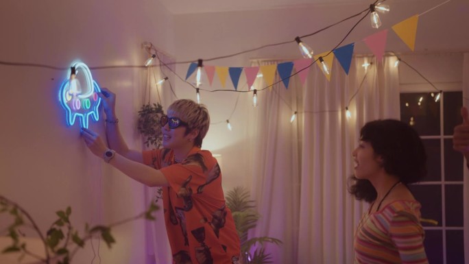 一群朋友来用灯装饰他们房间的墙壁，为新年聚会做准备。