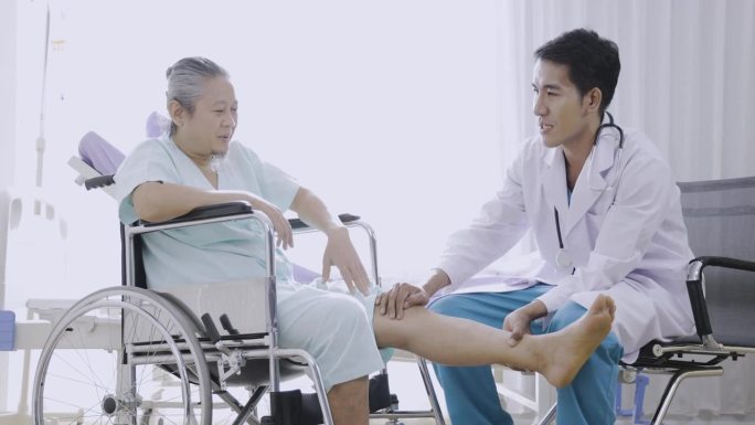 老人膝部疼痛，老人住院。亚洲医生照顾坐轮椅的老年病人。