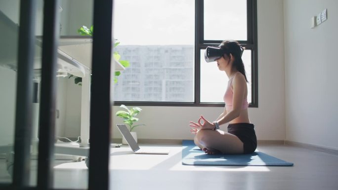 年轻女运动员戴着虚拟现实耳机练习冥想在现代未来的方式