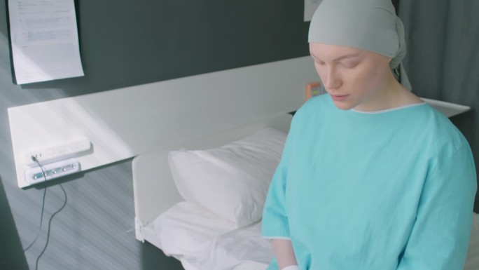 患癌症的年轻女子坐在床上看着镜头