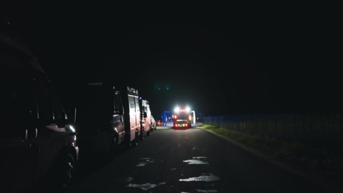 消防队员和消防车在夜间的道路上闪着蓝色的灯