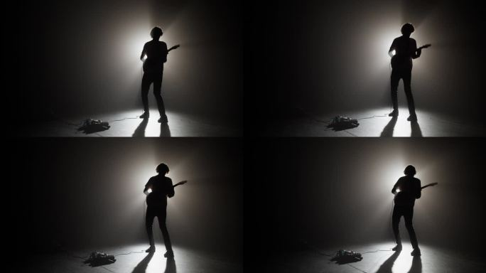 男吉他手的剪影在耀眼的聚光灯下表演