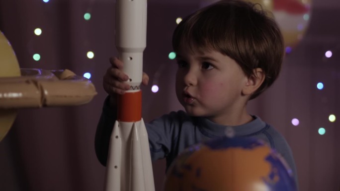 小男孩宇航员从太空港发射玩具火箭穿越行星。宇航员幻想在宇宙飞船上飞行。顽皮家庭室内的儿童飞行员。创意