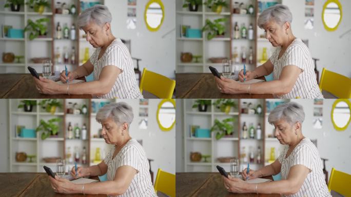 老年妇女一边看处方一边用智能手机