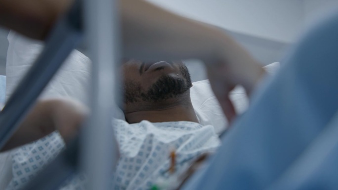 手术前，一名男子躺在轮床上与医生交谈