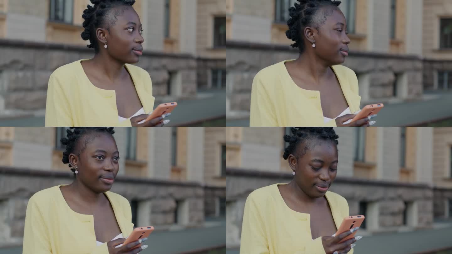 漂亮的非裔美国女人站在街上用智能手机看城市