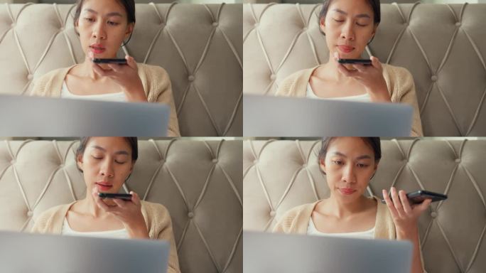 照片中的女孩把笔记本电脑放在床上，用智能手机向智能手机上的虚拟助手发出语音指令，在舒适的卧室里录制音
