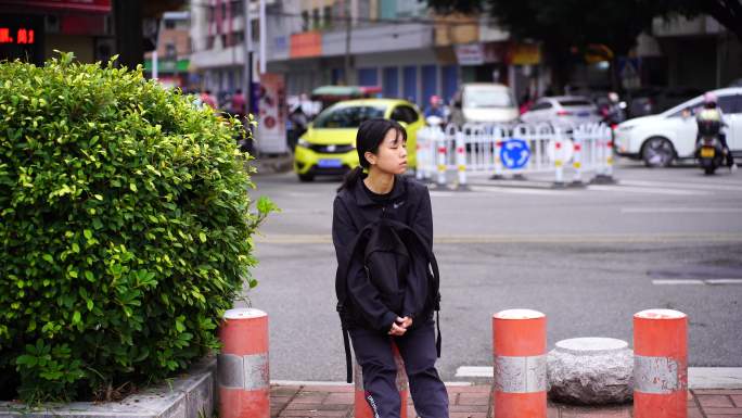 一个流浪的女人孤单的坐在街头柱子上打哈欠
