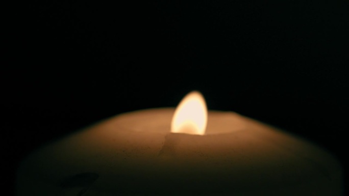 在黑色背景上，蜡烛火焰被风吹灭的特写镜头