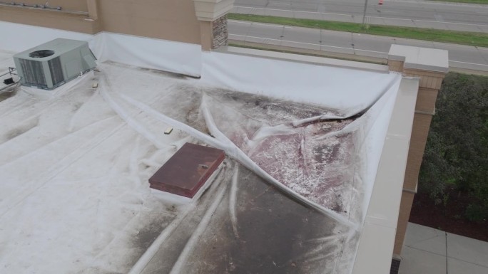 商业建筑屋顶损坏用白色篷布覆盖，空中动态