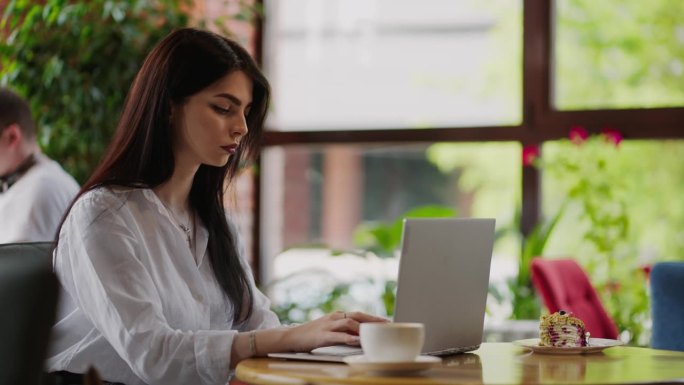 有吸引力的年轻成年女性在咖啡馆用笔记本电脑远程工作的肖像，女商人