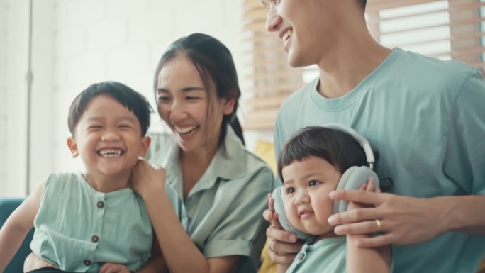 快乐的亚洲家庭在家里用耳机，慢动作
