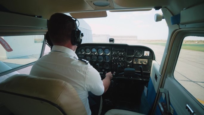 驾驶舱内的飞行员启动小飞机的引擎，准备起飞。螺旋桨旋转，飞机准备起飞。