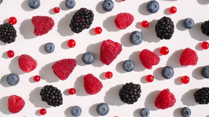 混合新鲜覆盆子，黑莓，蓝莓，红醋栗在一个孤立的白色背景顶部视图模式旋转。健康的水果浆果。新鲜水果小吃