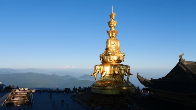 在晴朗的日子里，游客在峨眉山山顶祈祷的剪影，金色的蒲仙佛像以贡嘎雪山为背景的4k延时镜头。