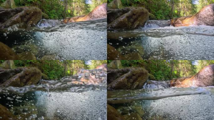 热带雨林中有一条清澈的河流。半水下的慢动作拍摄的溪流之间的石头与小瀑布。纯净的水和泡泡在丛林河