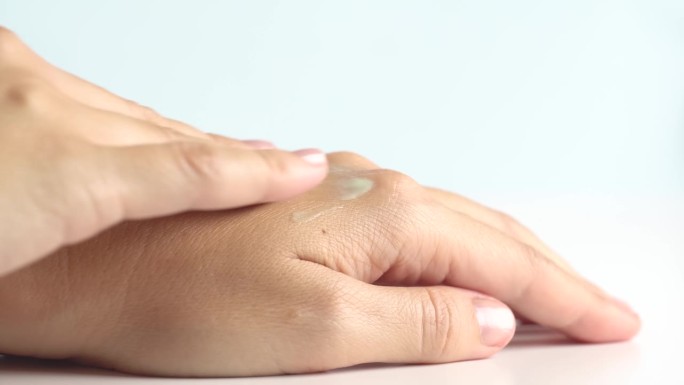 女性双手护理。一名女子将浅绿色的精华液凝胶涂在手皮肤上。含透明质酸的精华液，女性用手涂抹，护肤化妆品