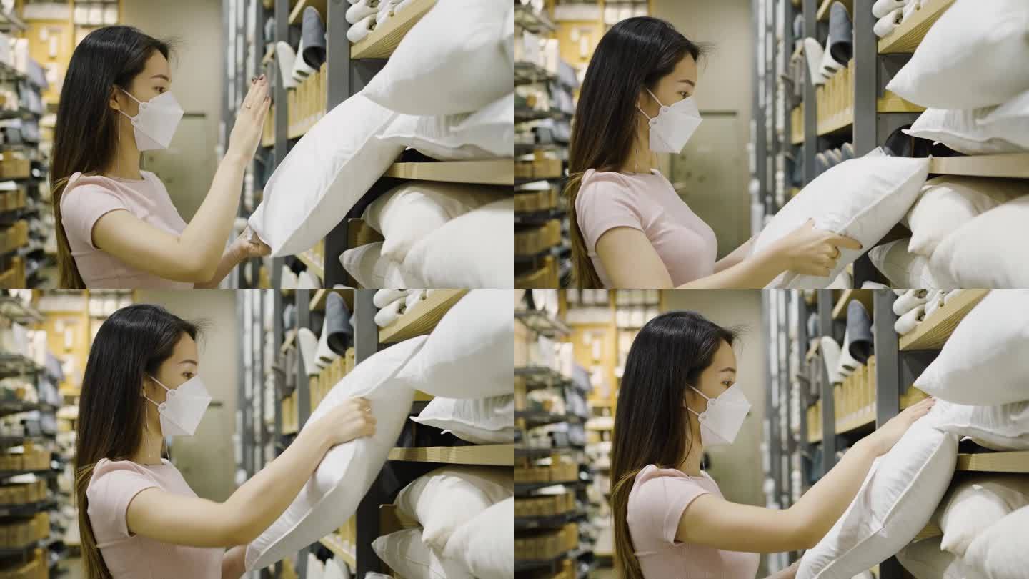 一名戴口罩的亚洲女性在零售商店选择床枕测试