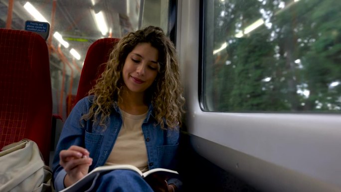 年轻女子在高速列车上微笑着写日记