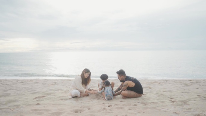 快乐的一家人在沙滩上玩耍，在日落时建造沙堡