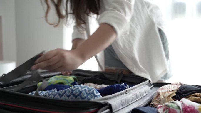女人打包行李在床上一个新的旅行行囊清单旅行计划，准备度假书现在旅行