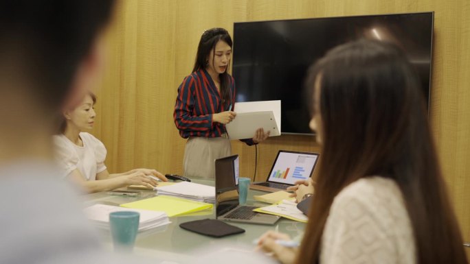 一名女工作人员目前正在向她的同事提交会议报告。