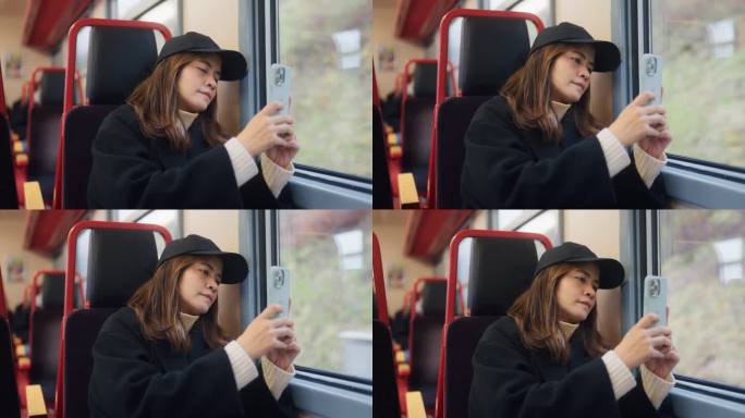 激动人心的亚洲女子乘火车到瑞士山区度假时，从窗户用智能手机拍照