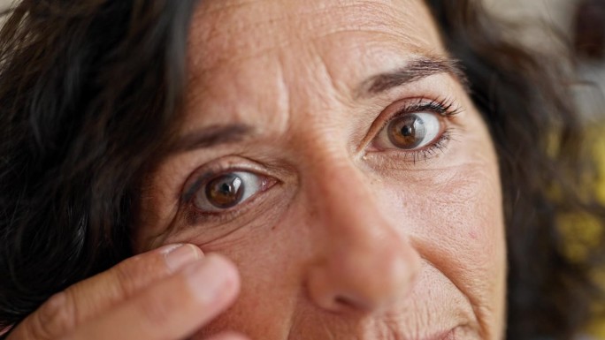 中年西班牙女人在家里摸着眼袋