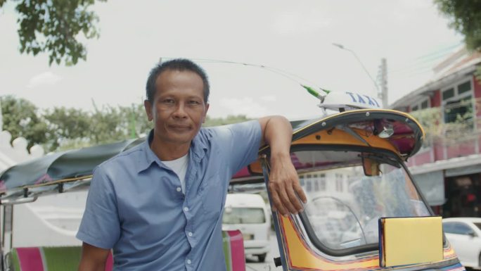 嘟嘟车司机和他的车站在曼谷老城区的道路上的肖像。