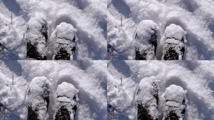 俯视图女子在雪中站在雪堆上，抖掉黑色靴子上的雪