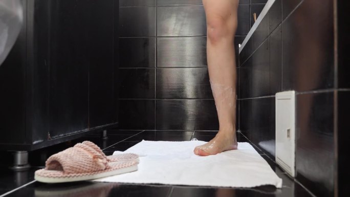 特写的女人湿腿在肥皂泡沫走出浴室。女性卫生，浴室放松，美容健康