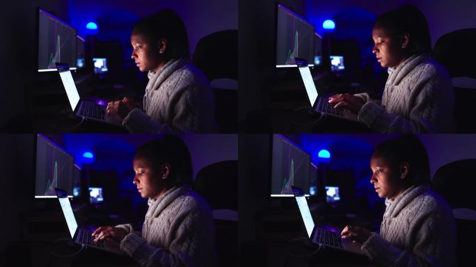 年轻的黑人女性在黑暗中用笔记本电脑键盘打字。主要是非裔美国女性工作。