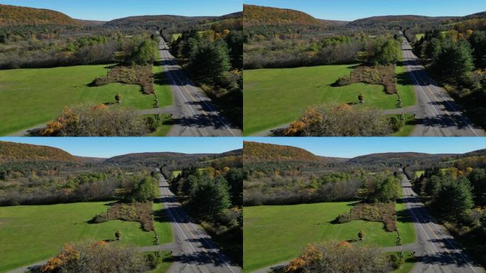 在乡村公路上行驶的汽车，背景是山脉(秋天，秋天的景色，树木变色)交通鸟瞰图(无人机镜头，从高空拍摄，