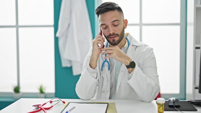 年轻的西班牙裔医生在诊所用智能手机通话，看手表