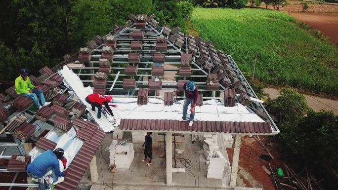 无人机拍摄的屋顶工人在屋顶上工作。