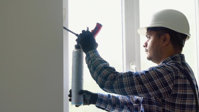 印度工人用密封胶管和吸力升降机在室内安装塑料窗