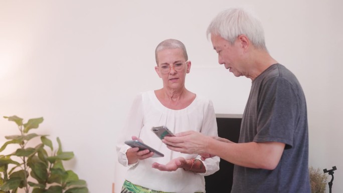 快乐的老年女性和男性使用智能手机和平板电脑