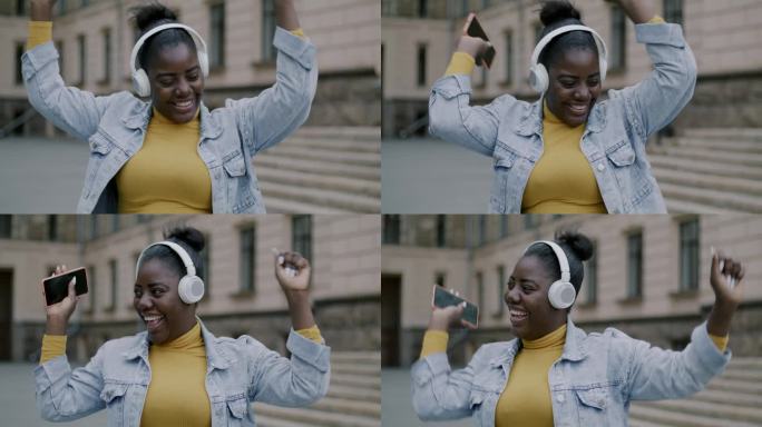 美丽的非裔美国女士戴着耳机听音乐，在城市户外跳舞的慢动作