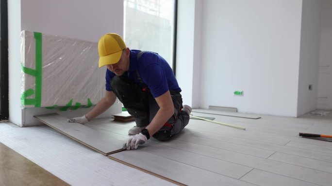 师傅安装浮动地板的工作，在地板上铺设强化板