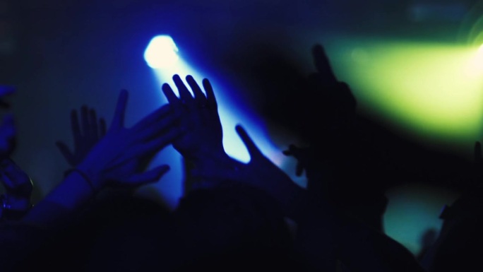 疯狂的人们在节日音乐会或夜总会聚会。年轻的观众对音乐和艺术家、dj或乐队在舞台上的表演感到兴奋。粉丝