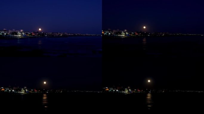 巨大的满月在天空中移动，发光并反射在海洋上。摄于葡萄牙埃斯托里尔