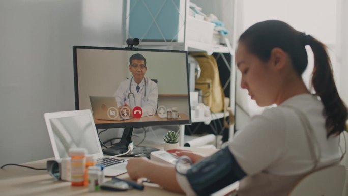 一名亚洲妇女在网上咨询医生时使用血压监测仪